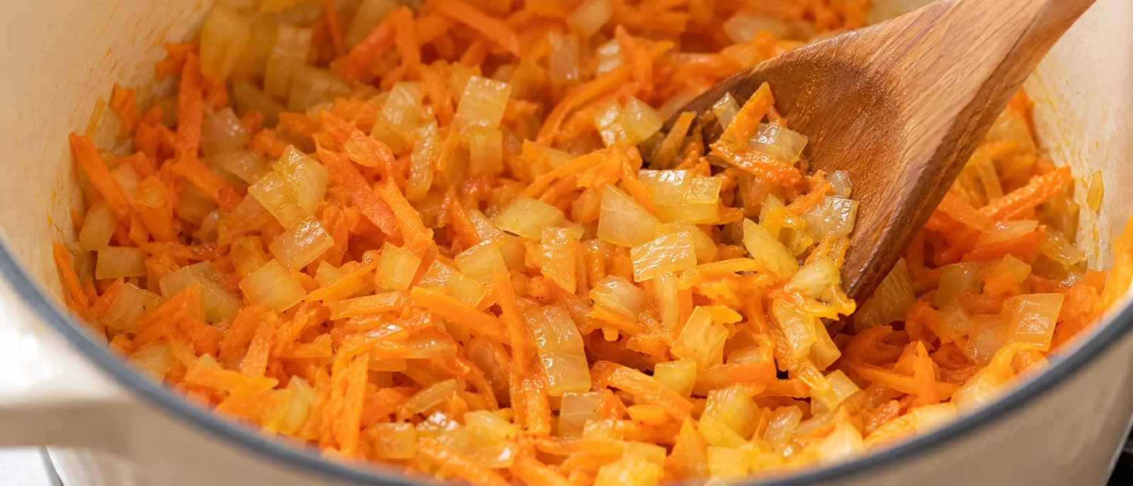 Onion and grated carrot softening in a saucepan
