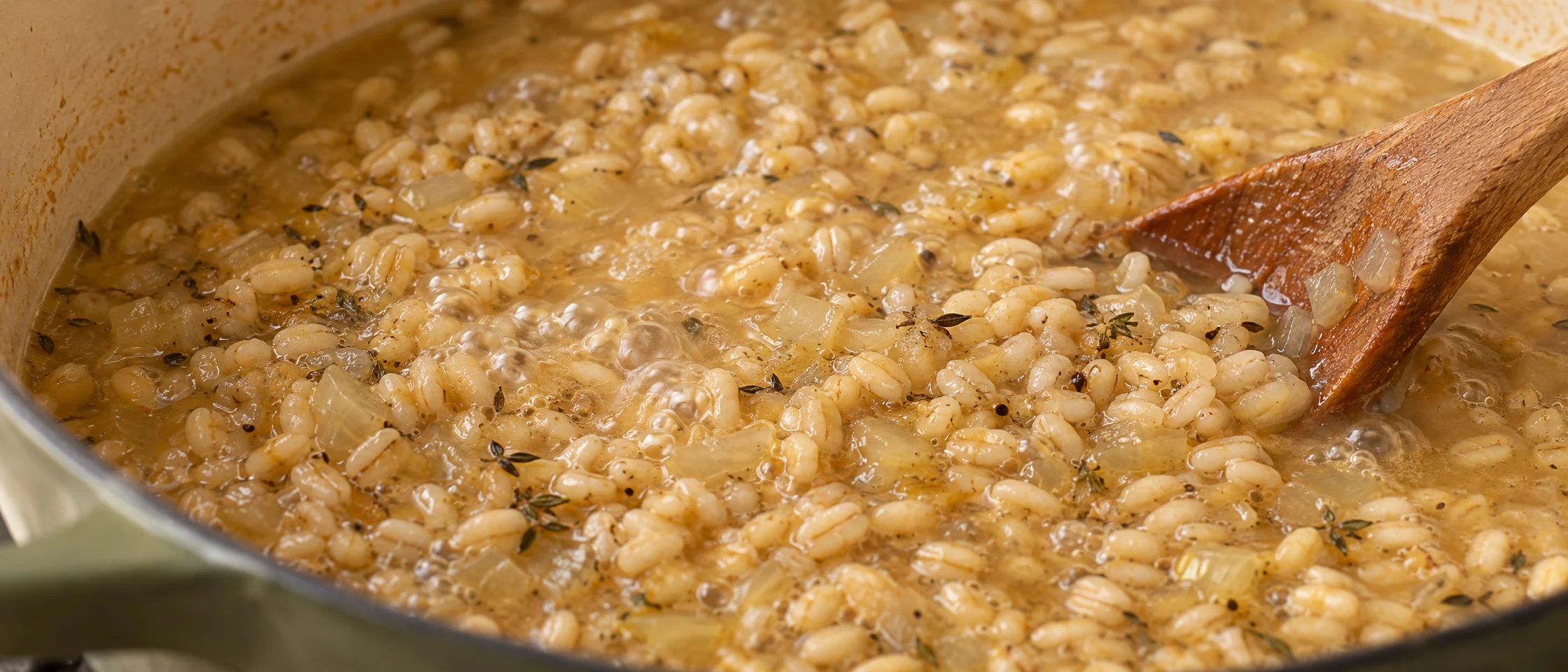 Pearl barley grains simmering with onion in stock