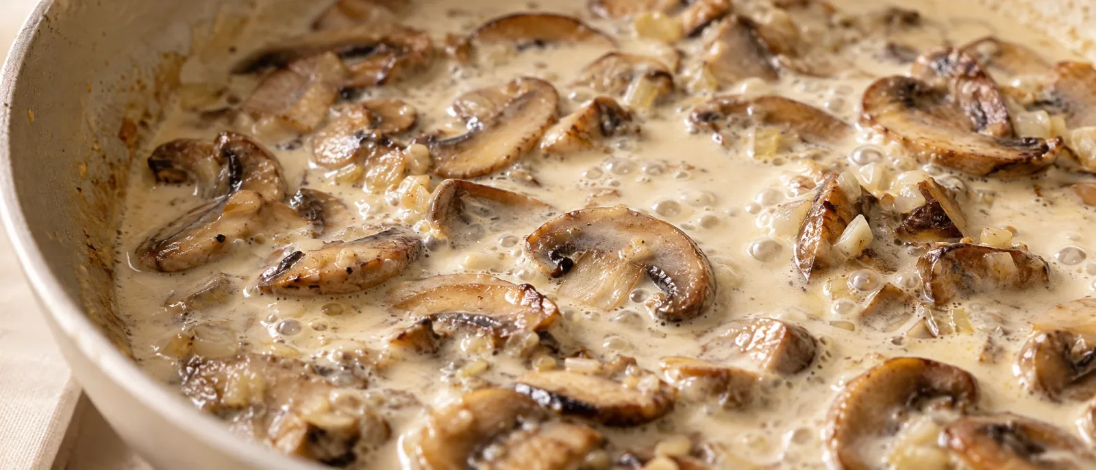Mushroom slices in a gently bubbling cream sauce
